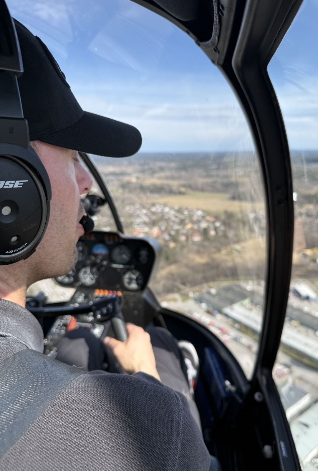 Pilot at the controls of a Robinson R44 above Stockholm