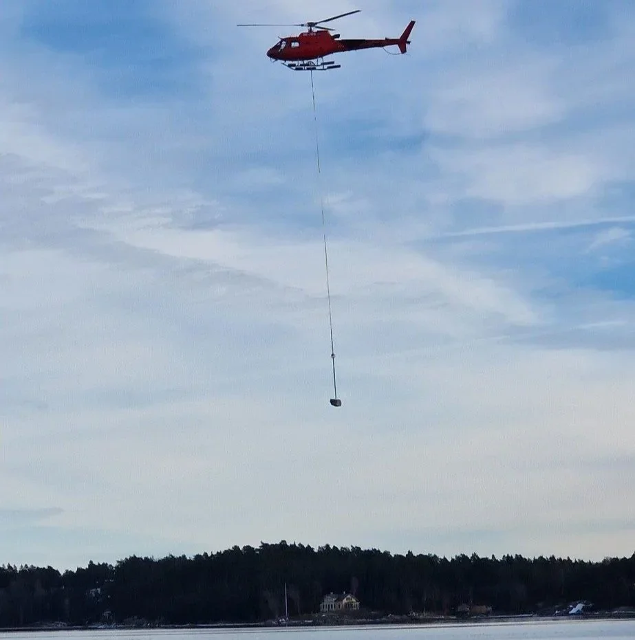 Red helicopter SE-JOS lifting cargo on a line over the Stockholm archipelago