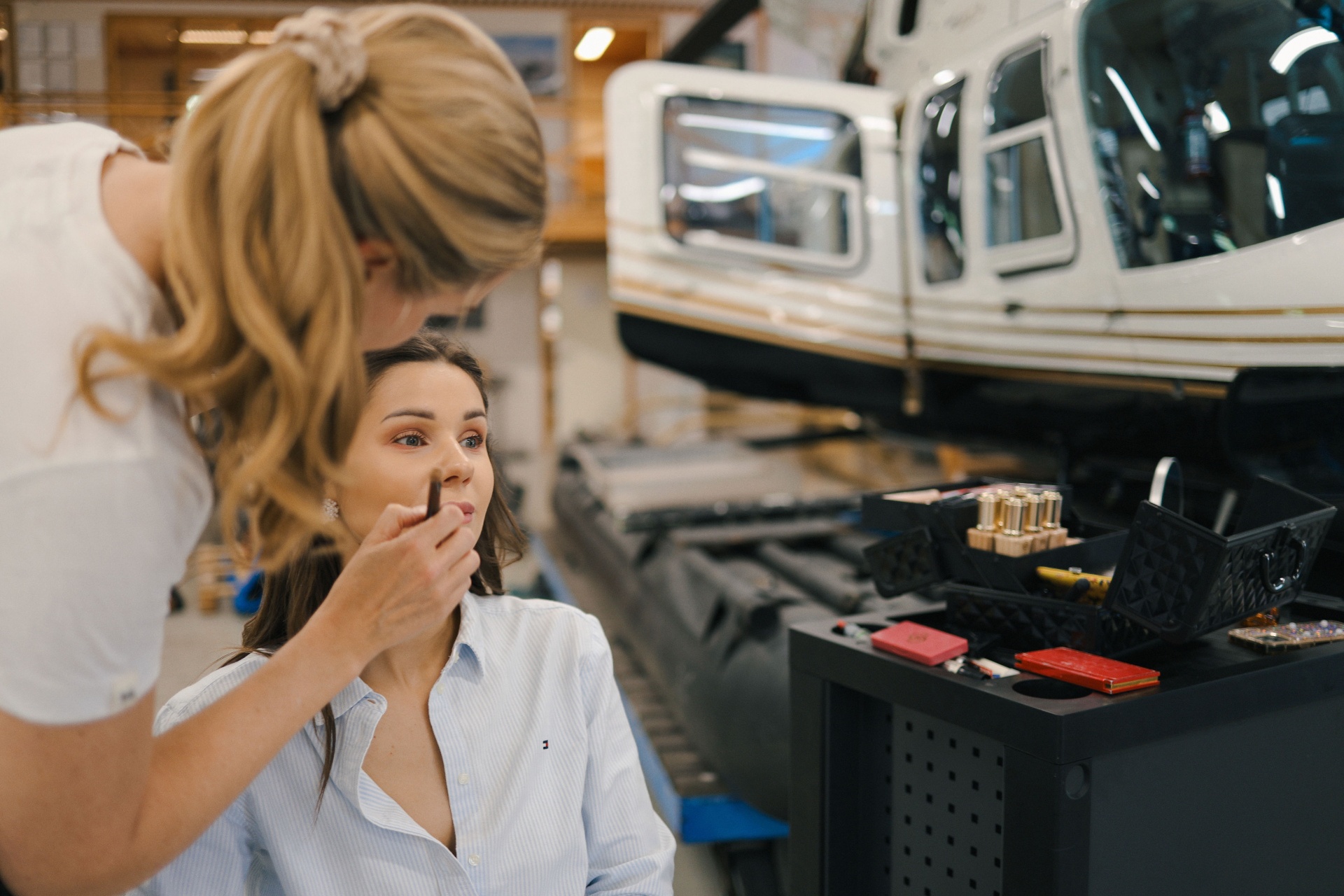 Bride having makeup done in the hangar in front of the helicopter