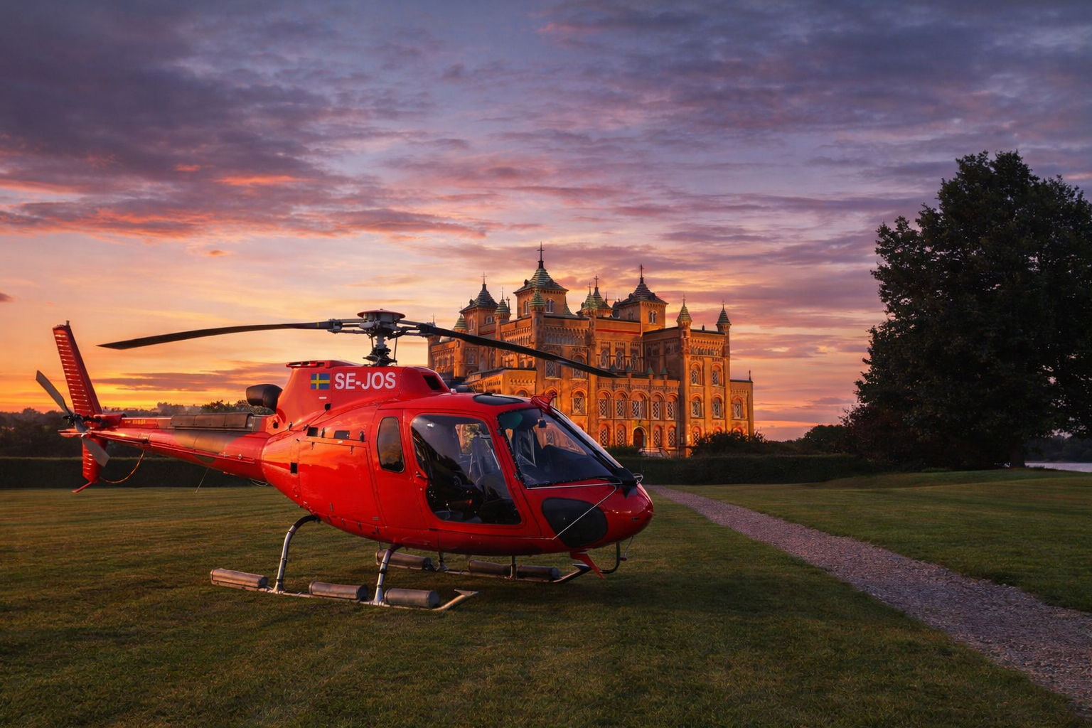 Red Airbus AS350 helicopter on the lawn in front of Stora Sundby castle at sunset