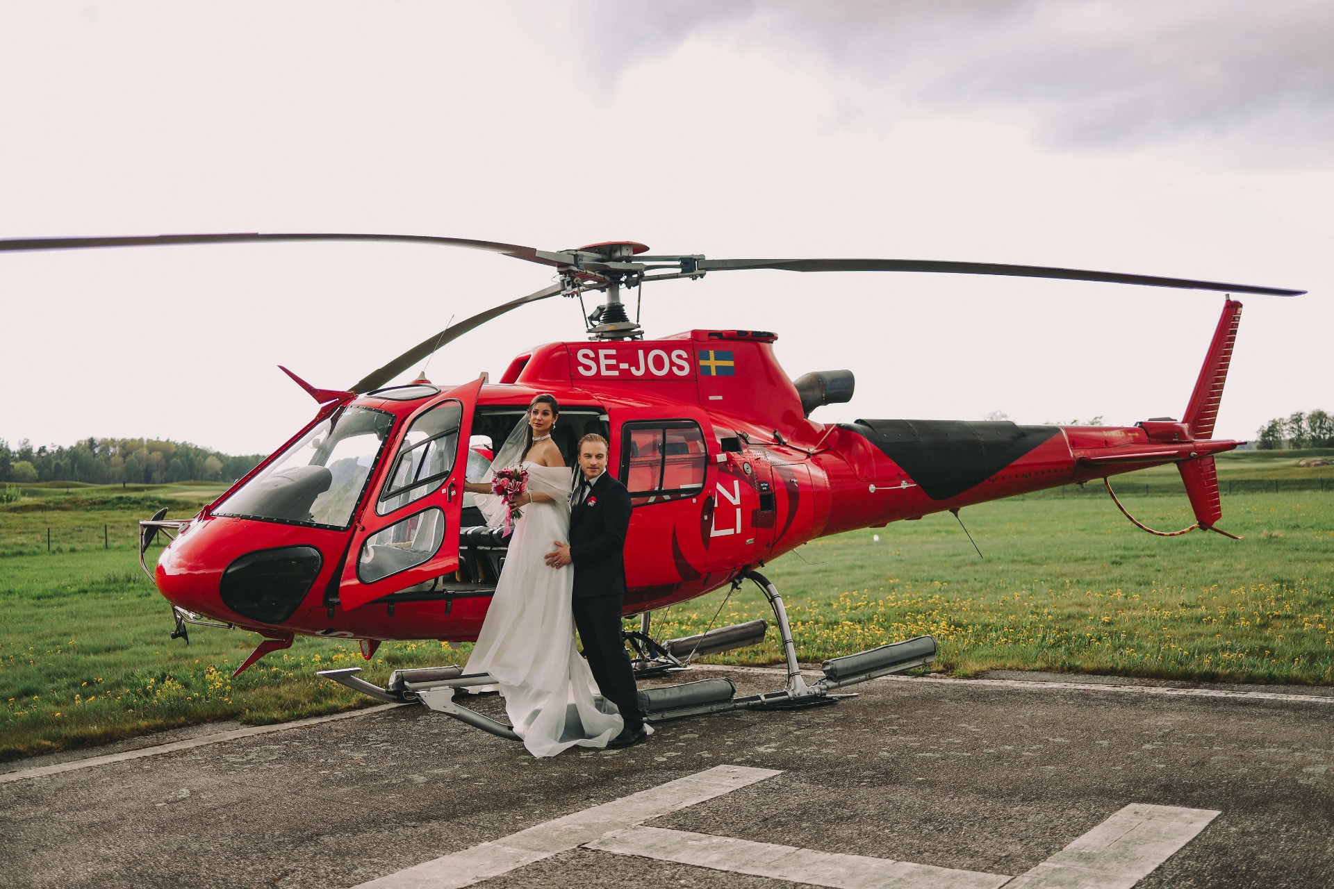 Bride and groom Karyna and Ludvig by the red helicopter SE-JOS