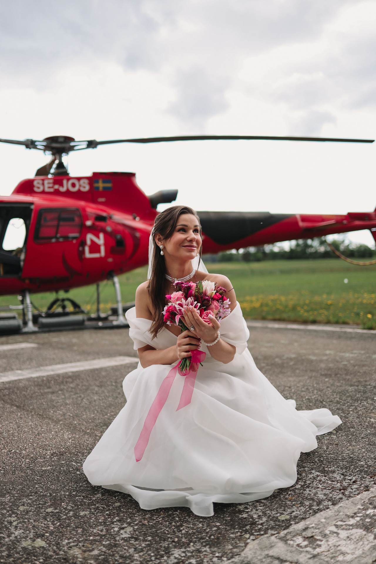 Bride sitting in front of the red helicopter SE-JOS