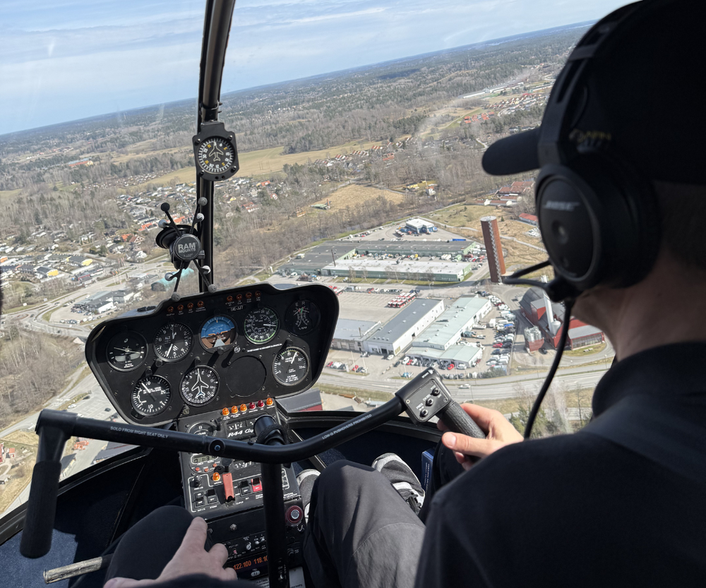 Student at the controls of a Robinson R44 above Stockholm
