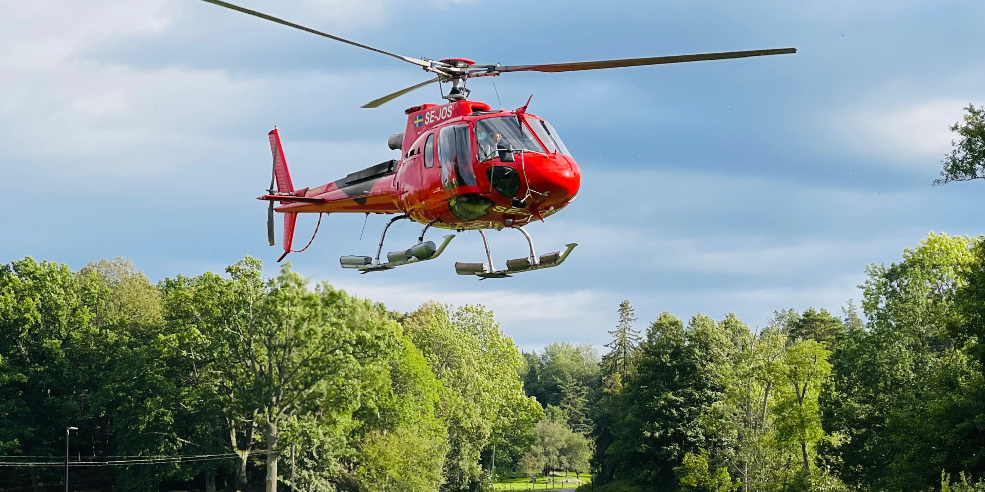 SE-JOS helicopter over forest during a survey mission